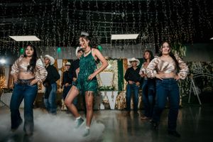 Dancers perform in sync on a misty dance floor with decorative lighting above.