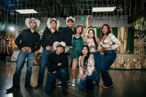 Group celebration photo with western attire and casual formal wear indoors.