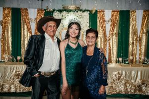 Event attendees pose against a gold and green backdrop with decorative lighting.