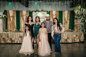 Small group poses together in formal wear against decorated gold and green backdrop.