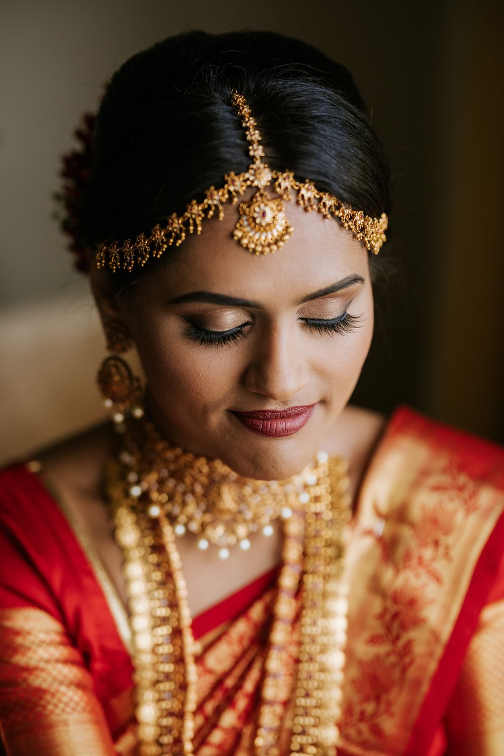 Traditional Indian bridal jewelry and makeup details with red and gold accents.
