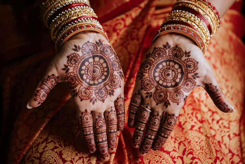 Intricate henna designs adorning hands decorated with traditional Indian bridal jewelry and bangles.