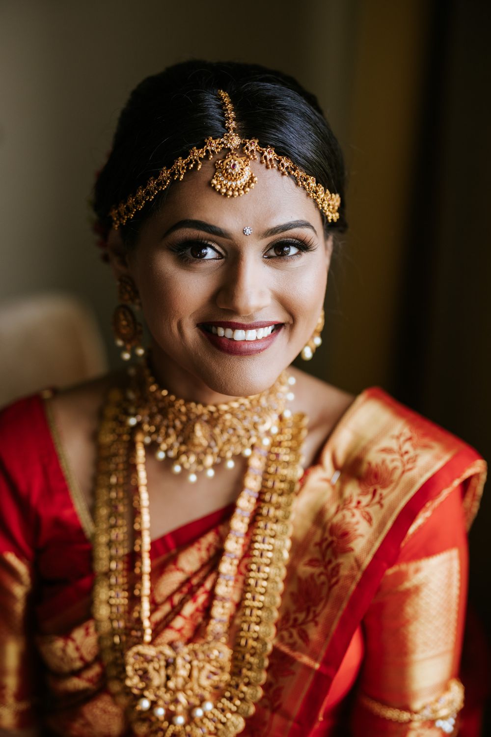 Traditional Indian bride wearing ornate gold jewelry and red saree smiles in a series of close-up portraits.