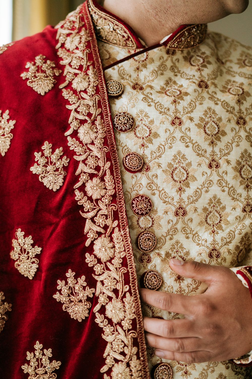 Close-up detail of red and gold embroidered Indian wedding attire with floral patterns.
