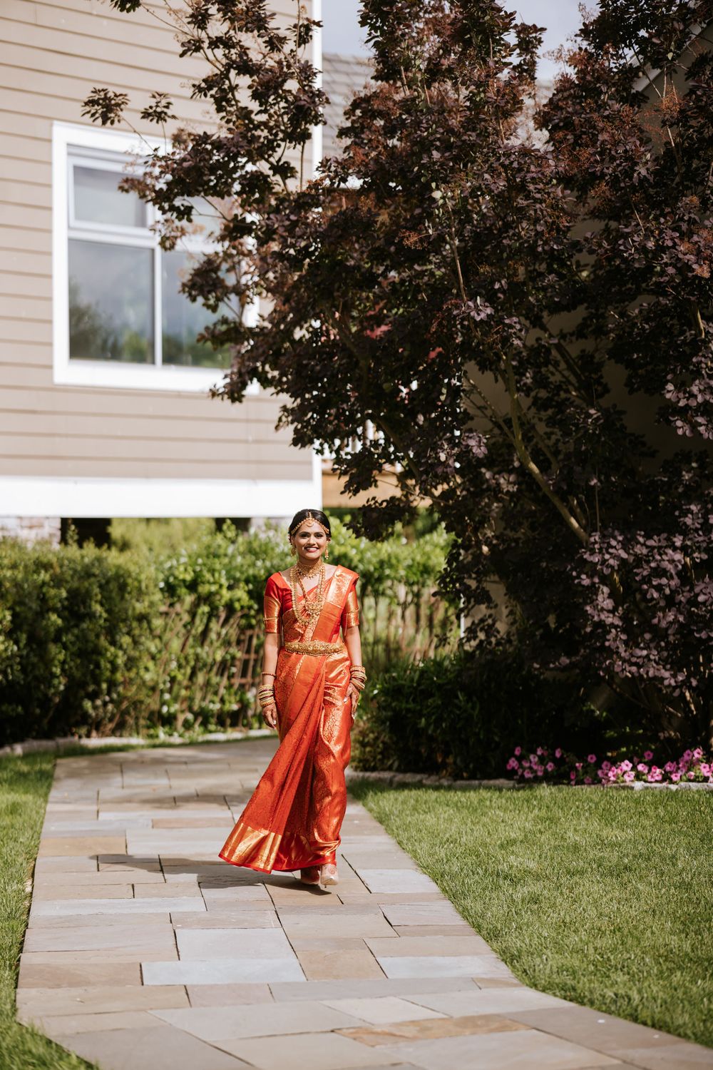 Traditional Indian wedding attire shown on a stone pathway in an outdoor garden setting.