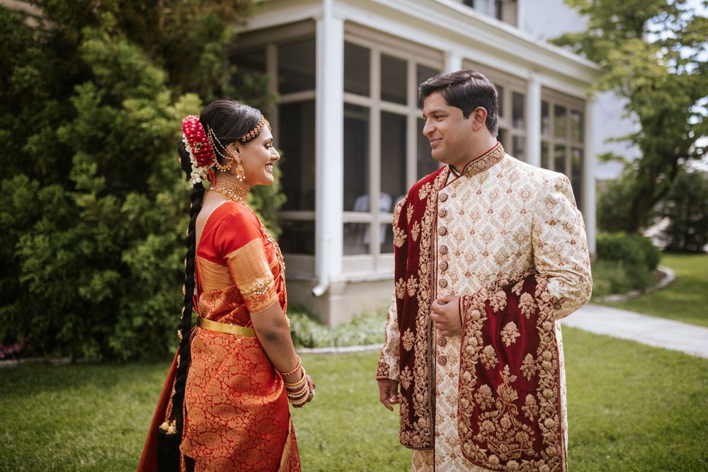 Outdoor wedding photography session featuring traditional Indian wedding attire against white colonial architecture.