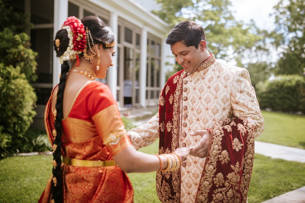 Couple in traditional Indian wedding attire standing together outdoors.
