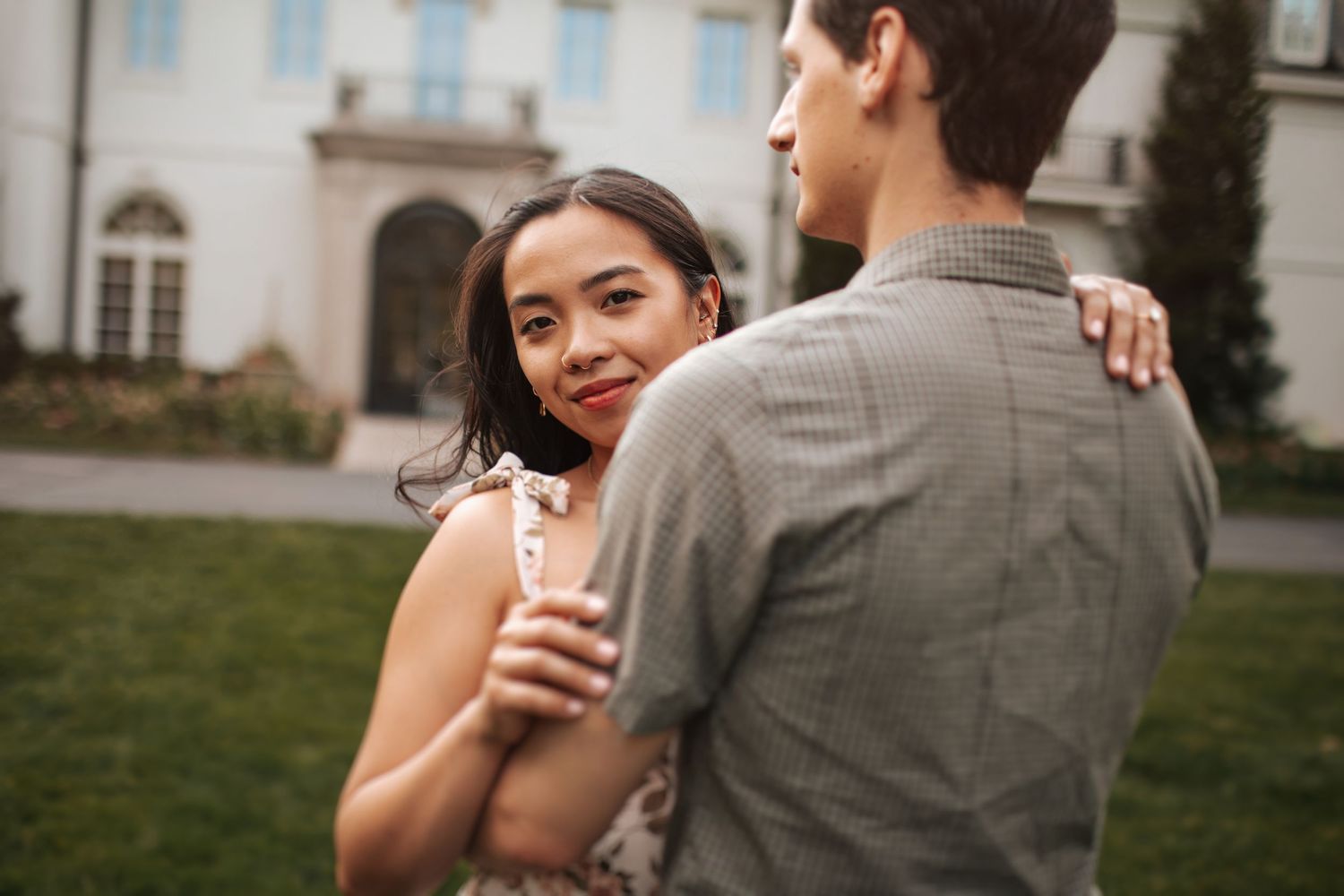 A couple embraces intimately outdoors at sunset with soft golden lighting.