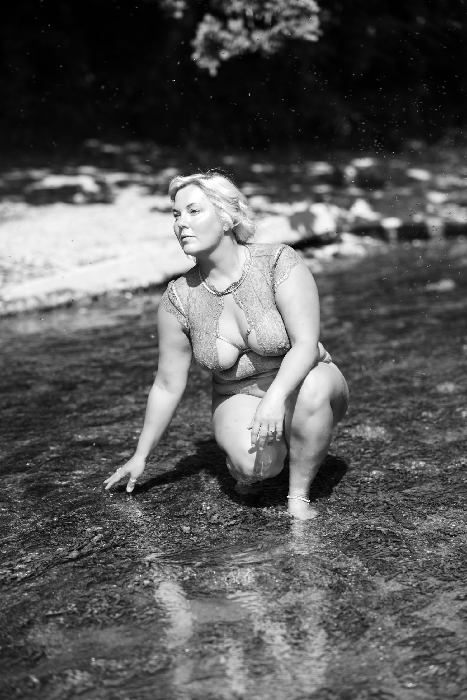 A person in a blue swimsuit sits on a stone ledge in a grassy outdoor setting.