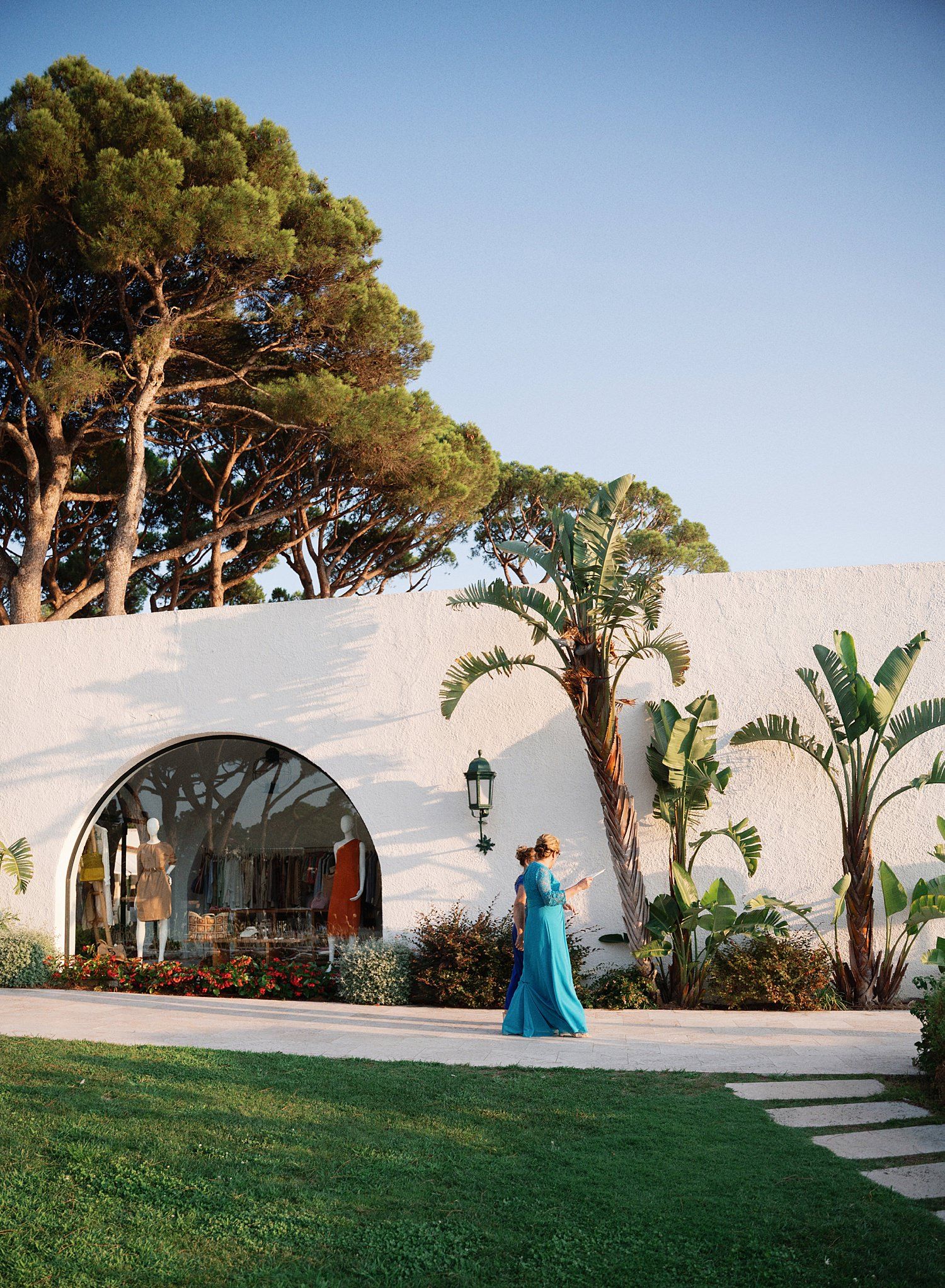 A series of outdoor wedding venue shots showing white walls, palm trees, and lush landscaping at sunset.