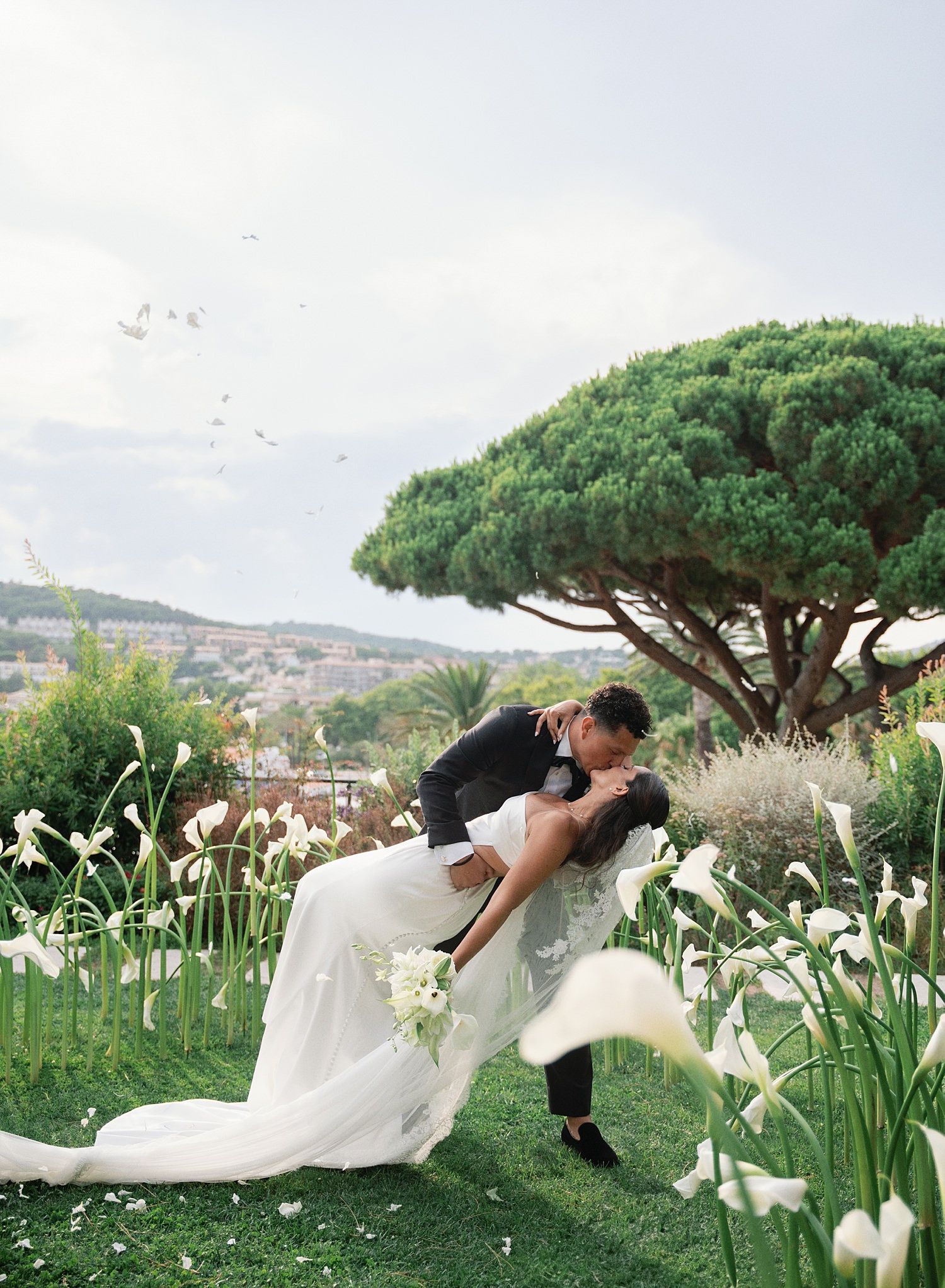 A romantic couple dances in a garden filled with blooming white iris flowers and towering umbrella pines.