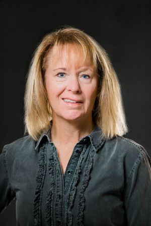 Business headshots featuring a black ruffled blouse against dark studio background.