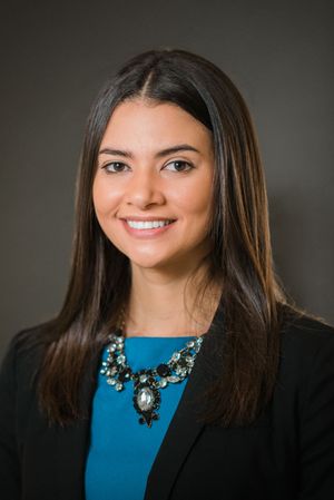Professional woman in black blazer and blue top with statement necklace in corporate headshots.
