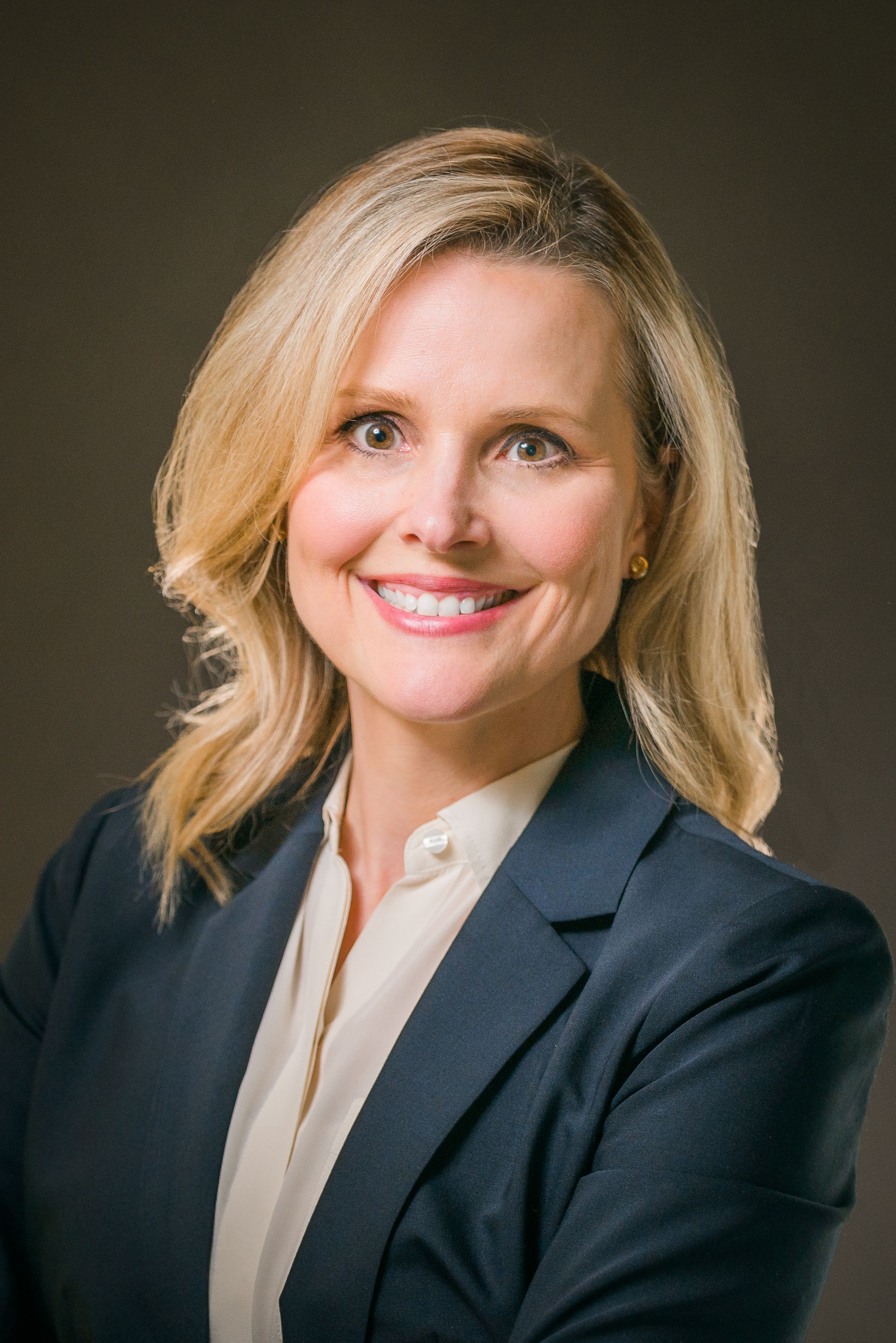 Professional woman in navy blazer and light blouse smiling in business headshot series.