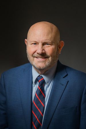 Professional in navy suit and striped tie shown in business portrait series.