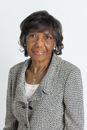 Professional portraits showing elegant style in black and white patterned blazer against white backdrop.