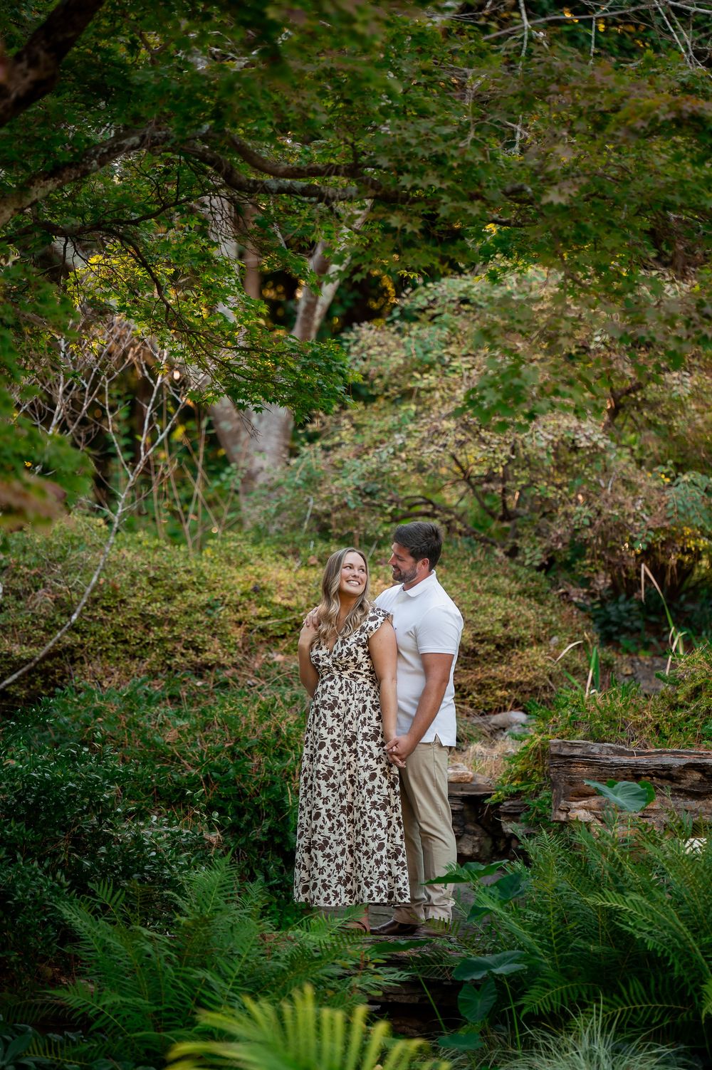 Romantic garden photoshoot with couple among ferns and natural landscaping.