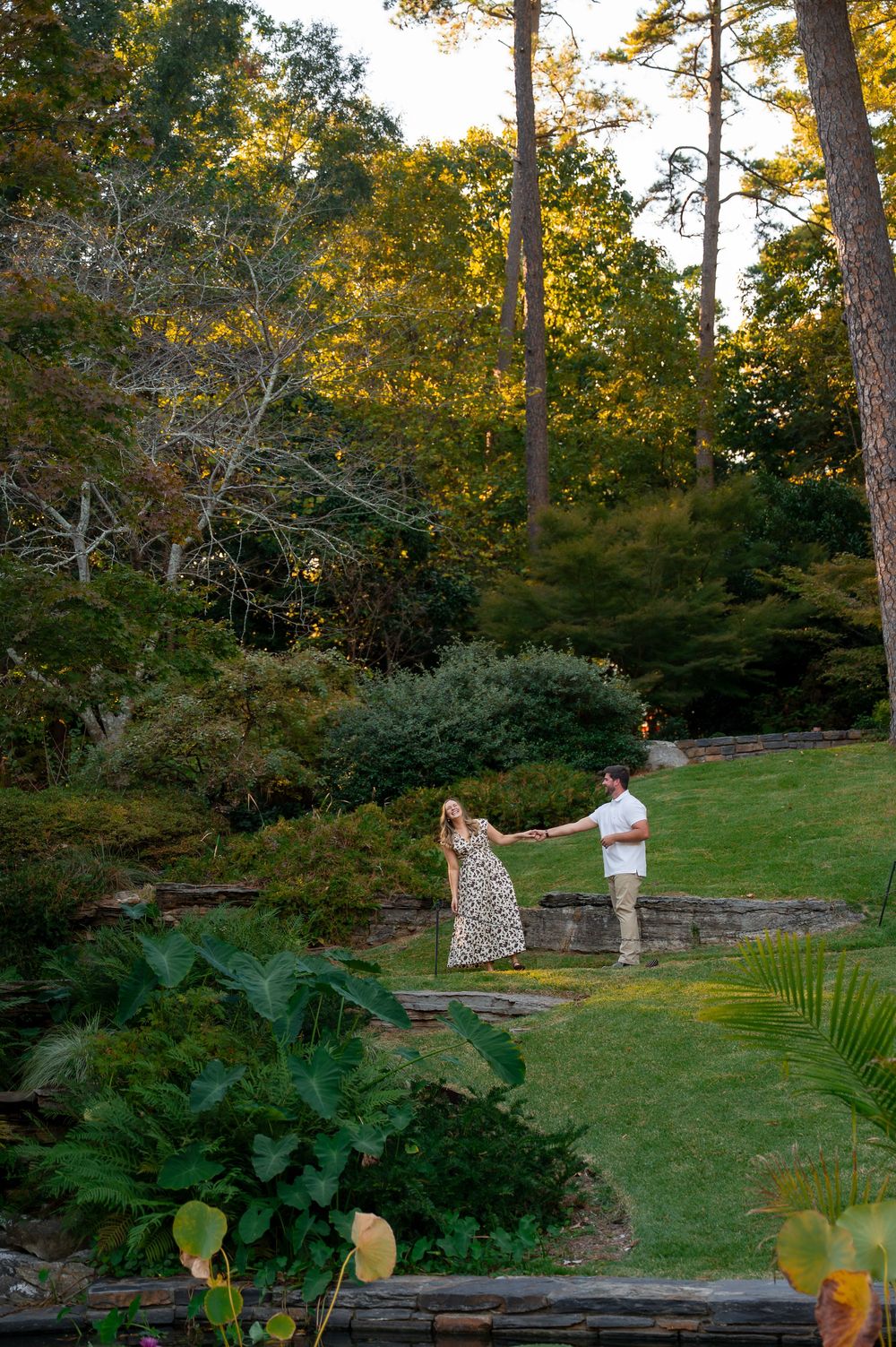 Couple enjoying a romantic moment in a lush garden setting with stone walls.