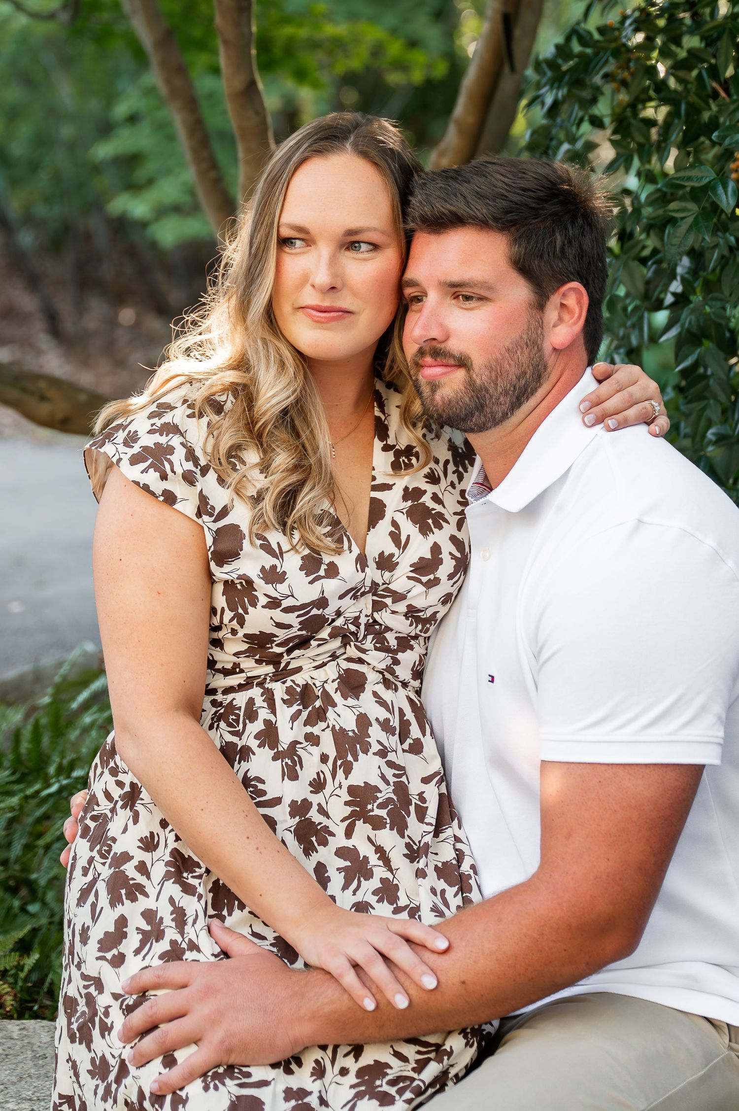 Loving couple in white and floral print embracing in a garden setting.