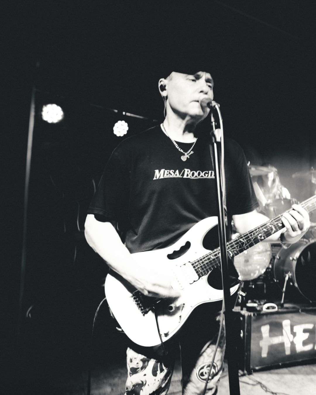 Black and white concert photography showing guitarists performing on stage.