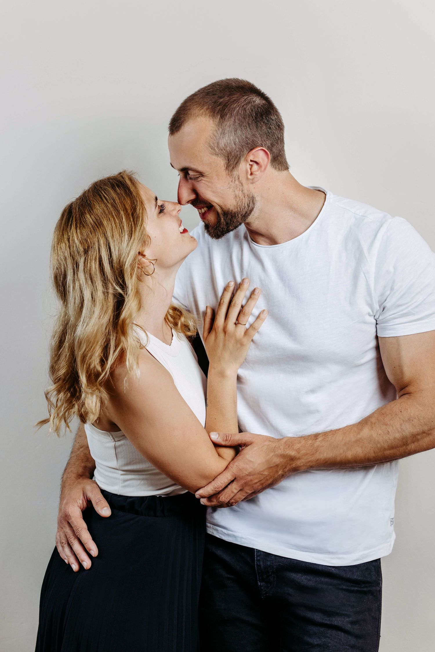 A couple in white and black outfits share an intimate embrace in a romantic photoshoot sequence.