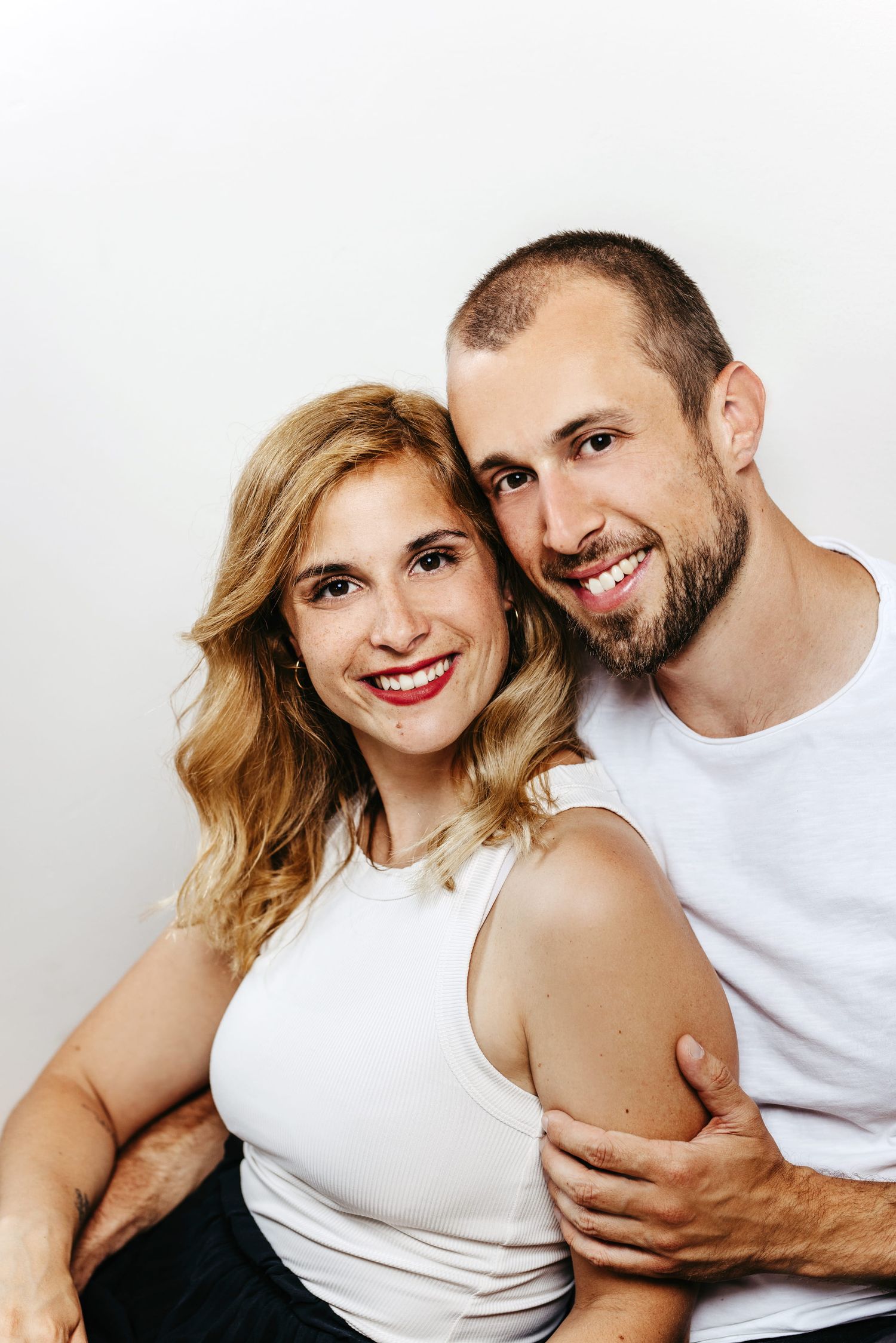 A couple in white clothing shares intimate moments in a series of romantic portrait photographs.