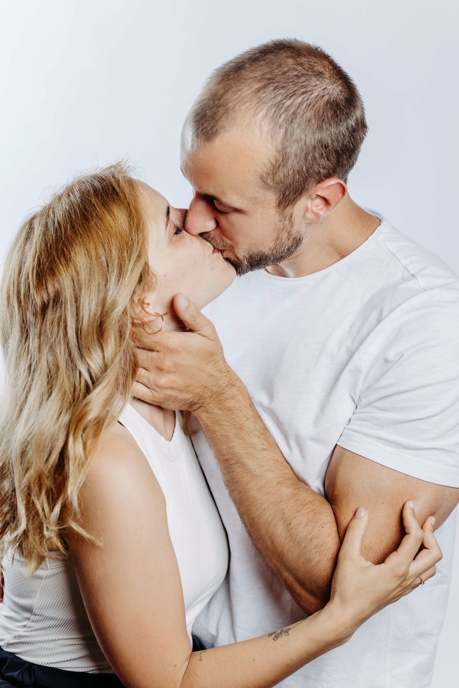 Romantic couple in white shirts share intimate kisses in a series of tender black and white photographs.