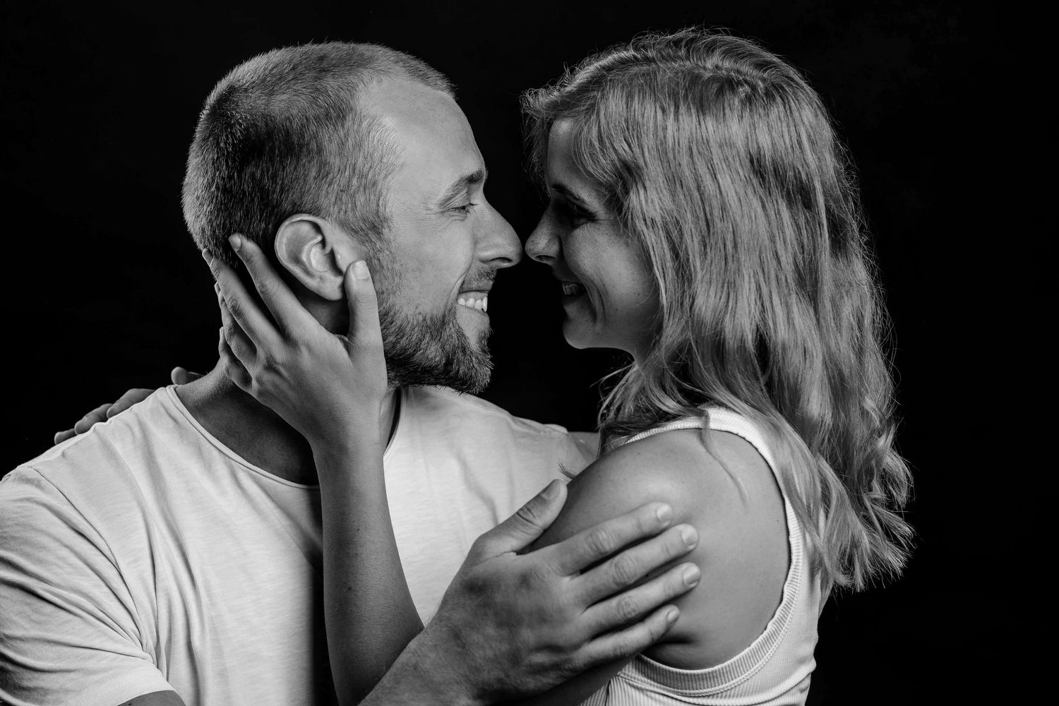 Intimate black and white portrait of a couple in tender embrace sharing a romantic moment together.