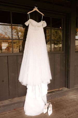 White flower girl or baptism dresses hanging on display against a dark wall.