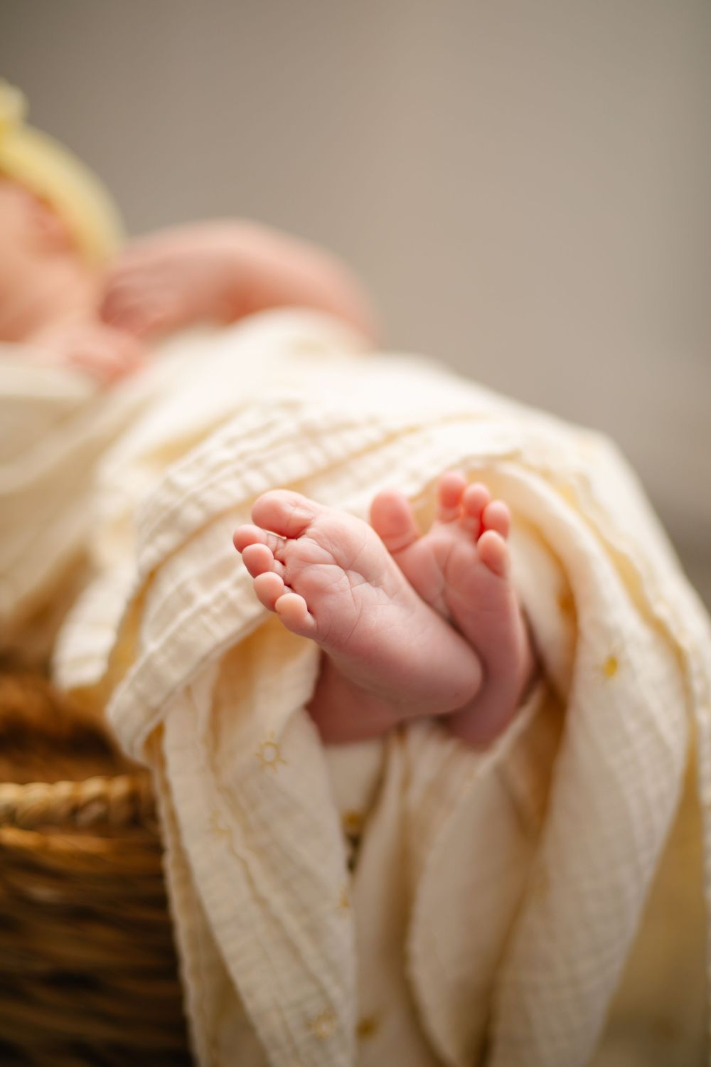Delicate baby toes peeking out from cream-colored wrap on wooden surface.