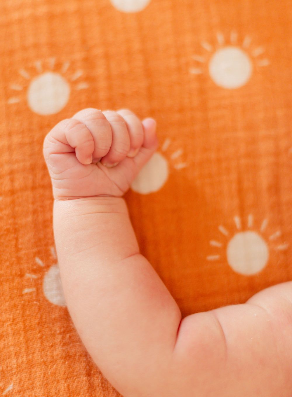 Baby feet against bright orange polka dot background.