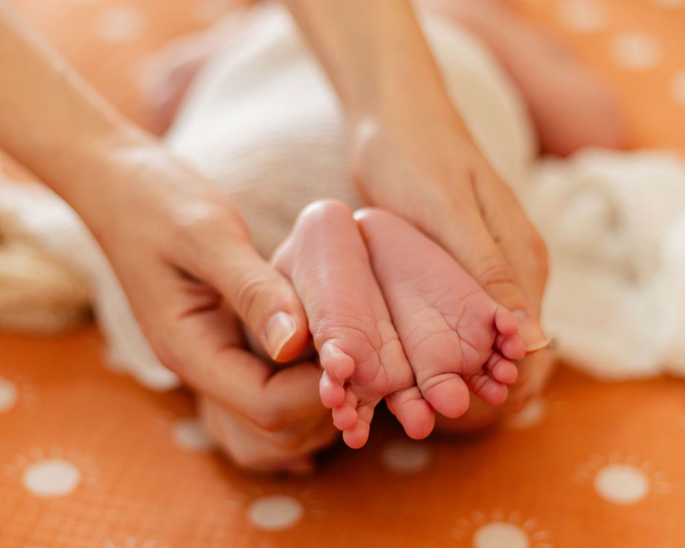 Tiny feet resting on orange dotted background with white fabric.