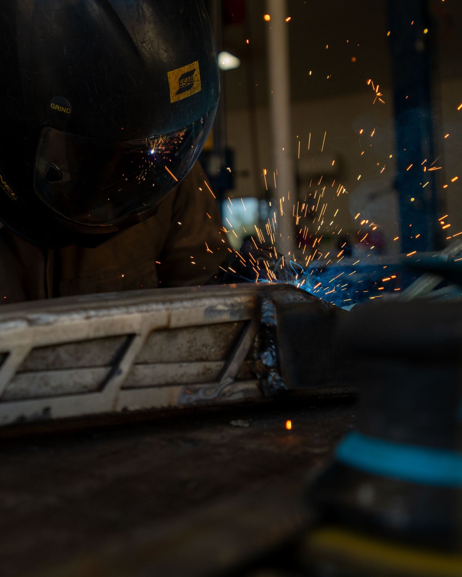 Close-up of welding sparks flying in dark industrial setting.
