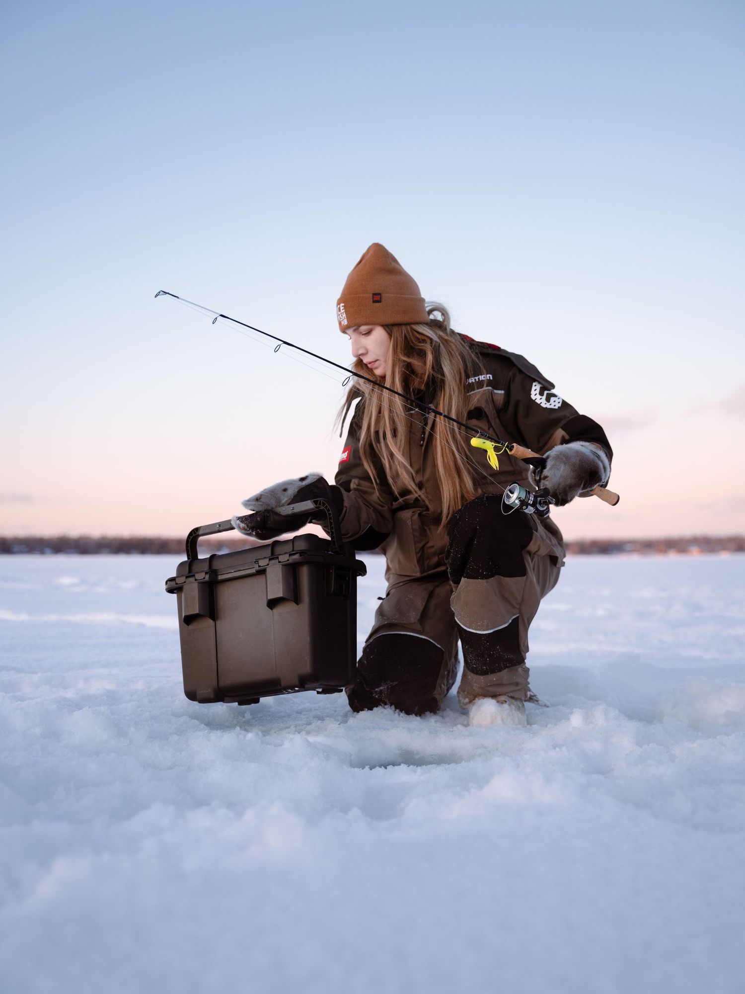 Ice fishing setup with equipment and tackle box on a frozen lake during winter.