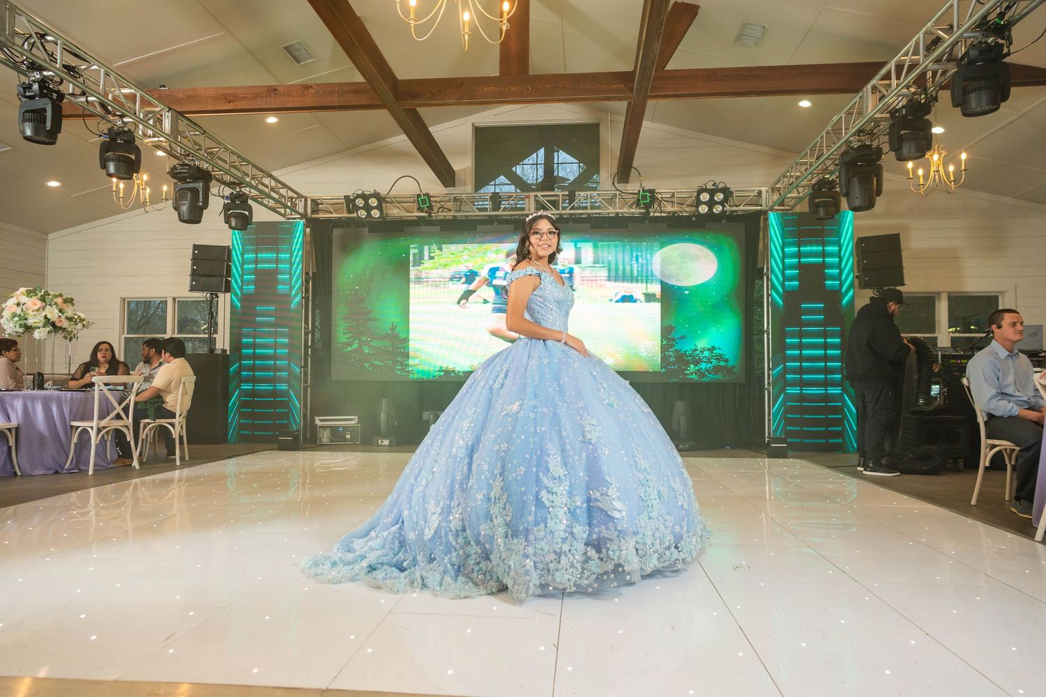 A large ballroom decorated in turquoise and white with elegant chandeliers and wooden beams on the ceiling.