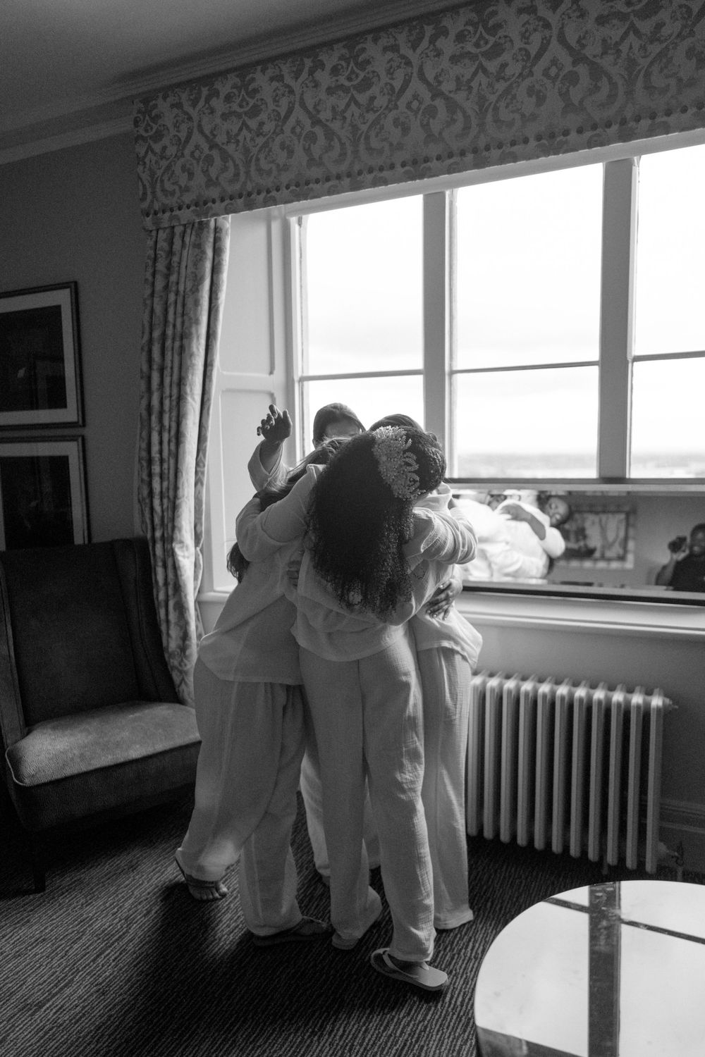 A tender black and white moment captured by a window in an elegant room.