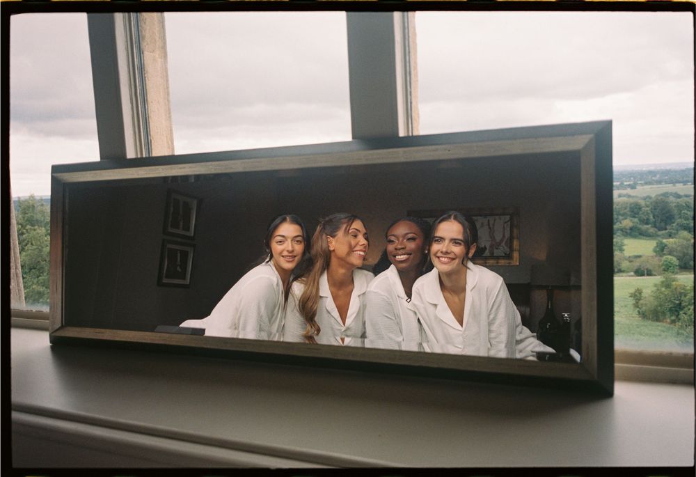Four people in white lab coats lean over a window ledge to look outside at a scenic landscape view.