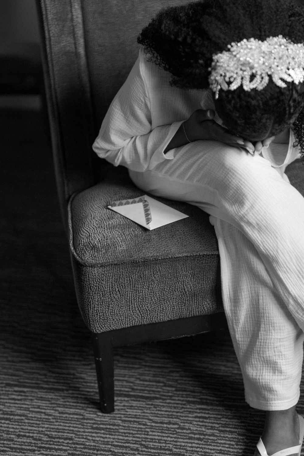 Black and white detail shot of wedding dress fabric and accessories on dark furniture.