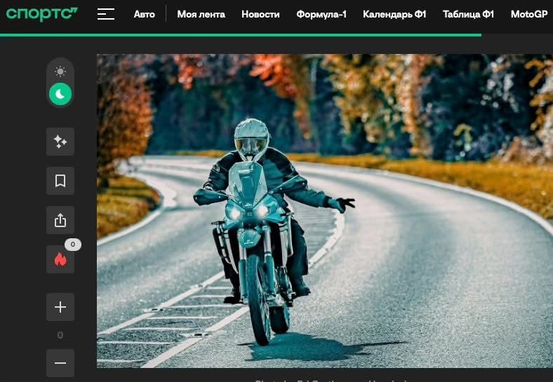 Motorcyclist in turquoise jacket riding on curved mountain road during autumn season with orange foliage.