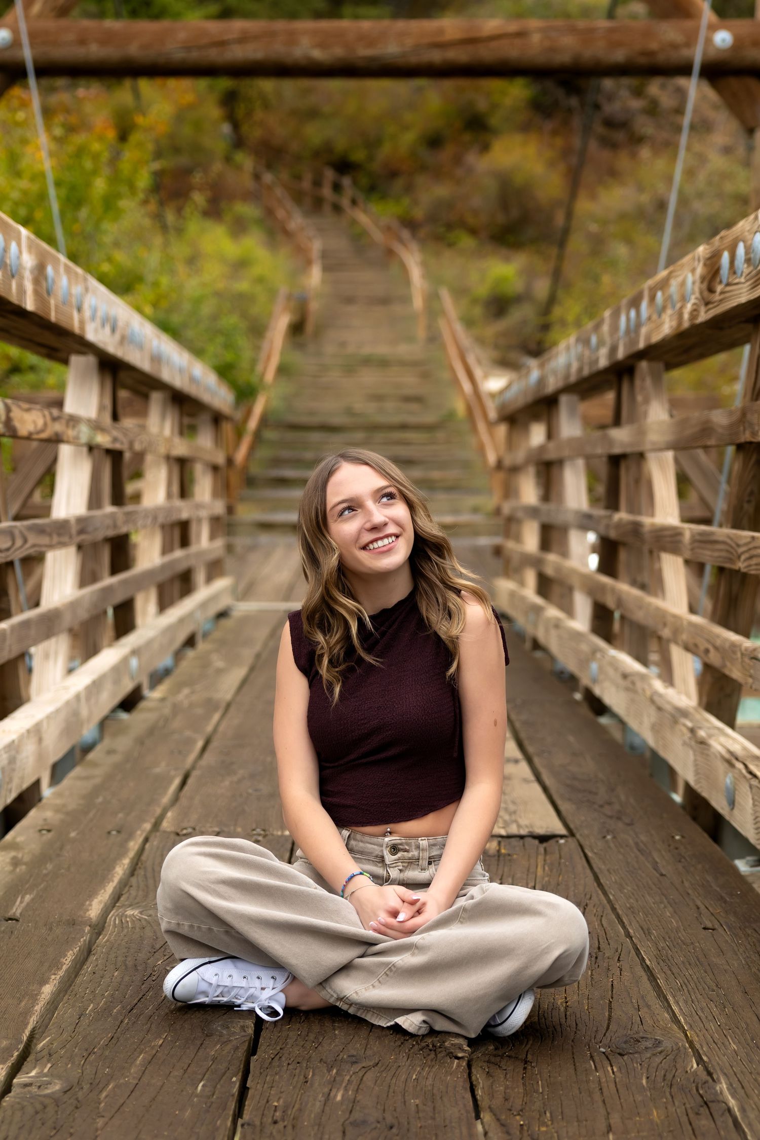 A wooden bridge walkway surrounded by autumn foliage creates a rustic outdoor scene.