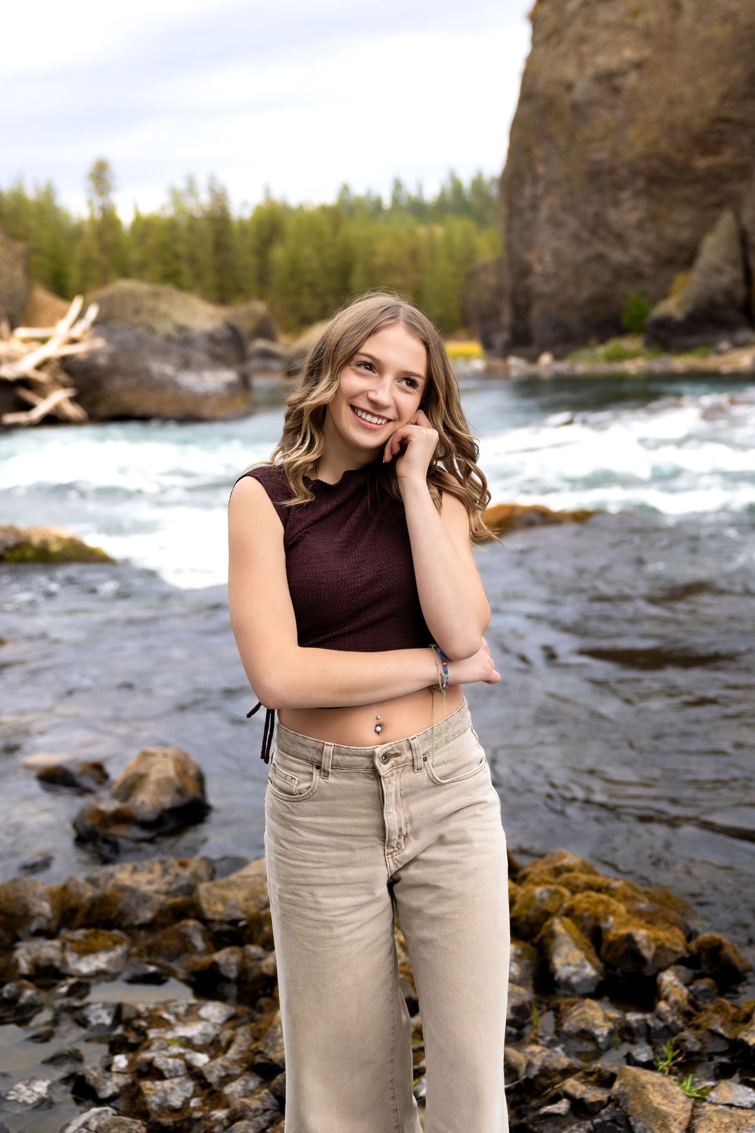 Portrait series by a rushing river with rocky shores and natural scenery in the background.