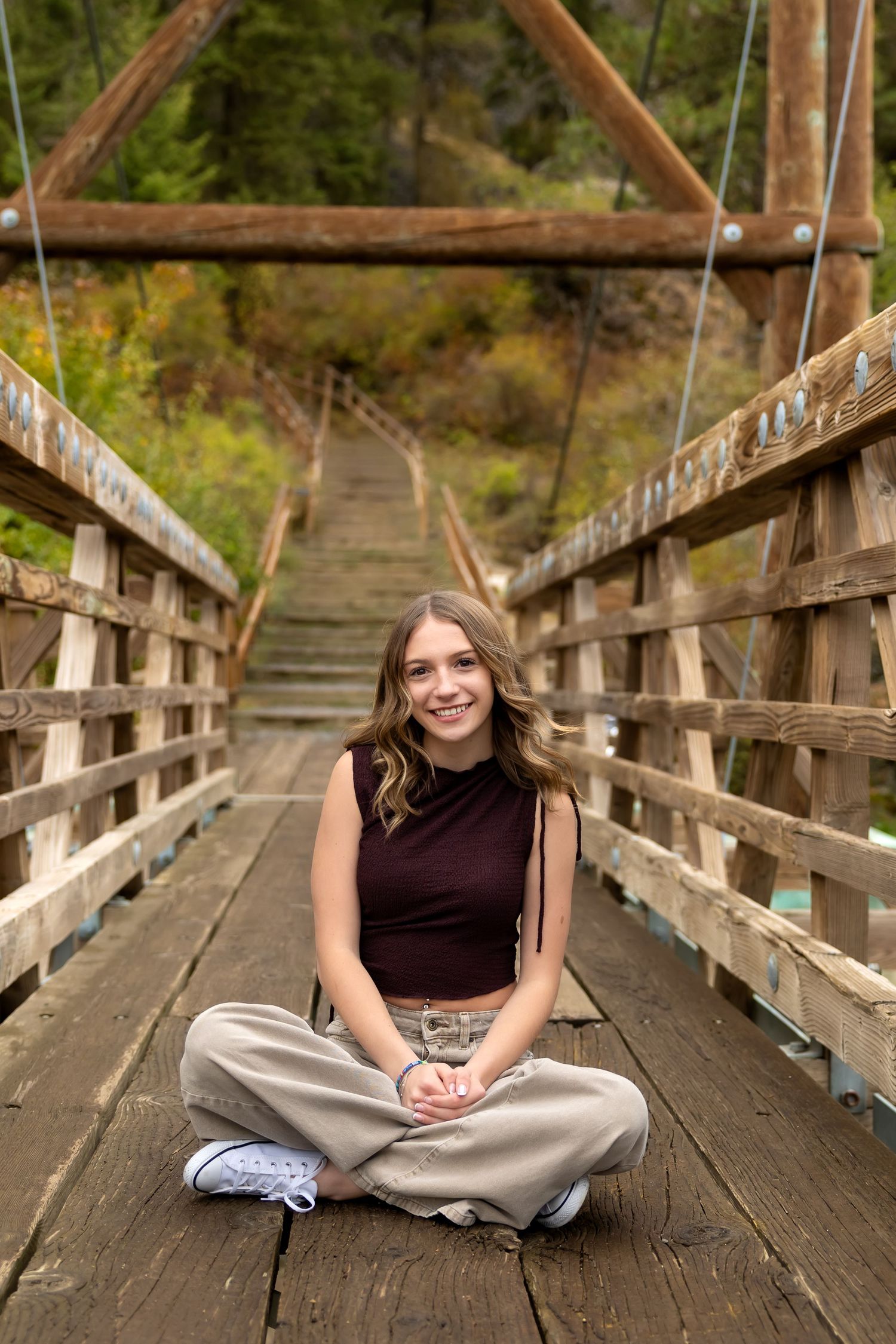 A series of outdoor portrait photos taken on a rustic wooden bridge surrounded by green forest scenery.