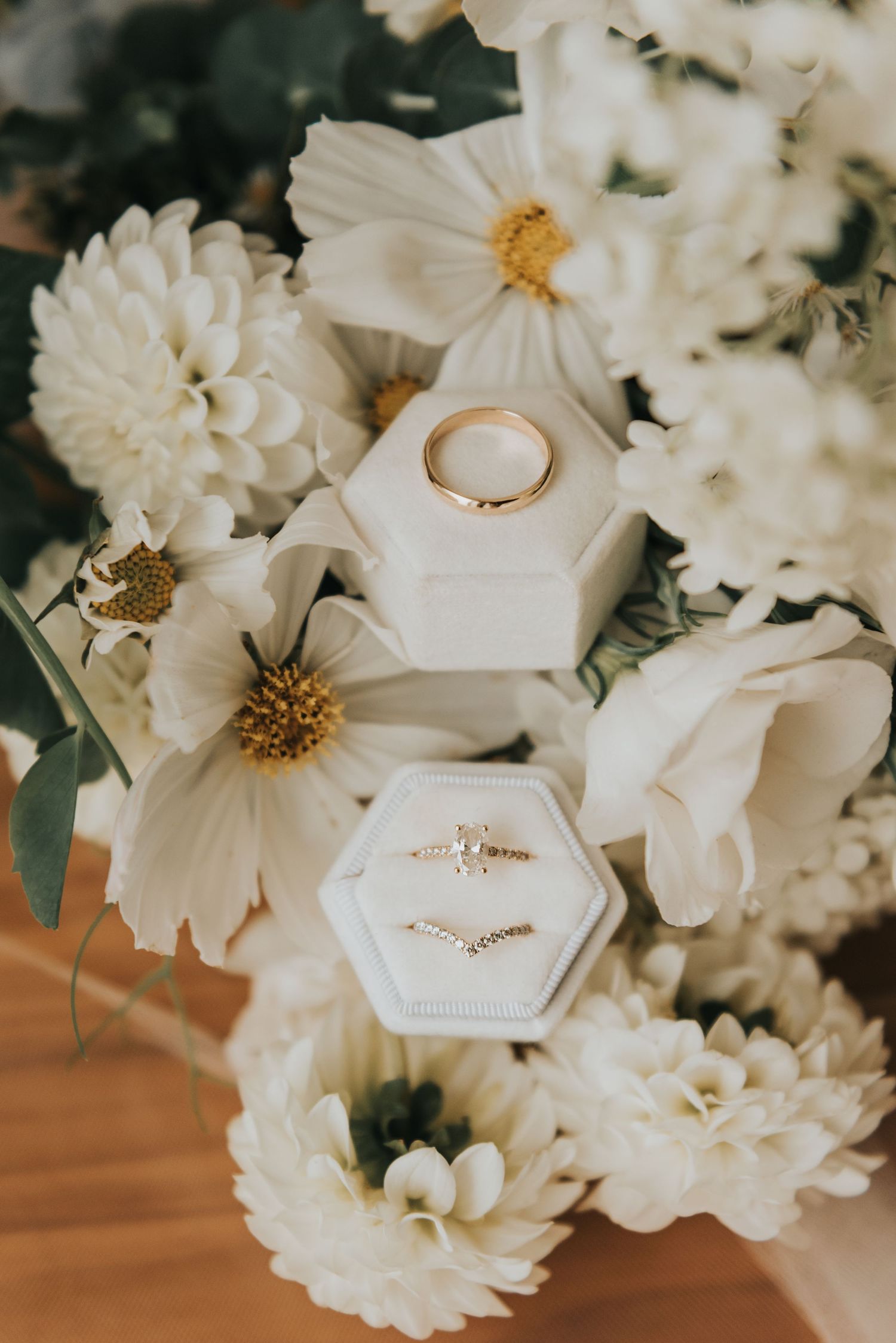 Wedding rings nestled among white dahlias and flowers on a hexagonal display.
