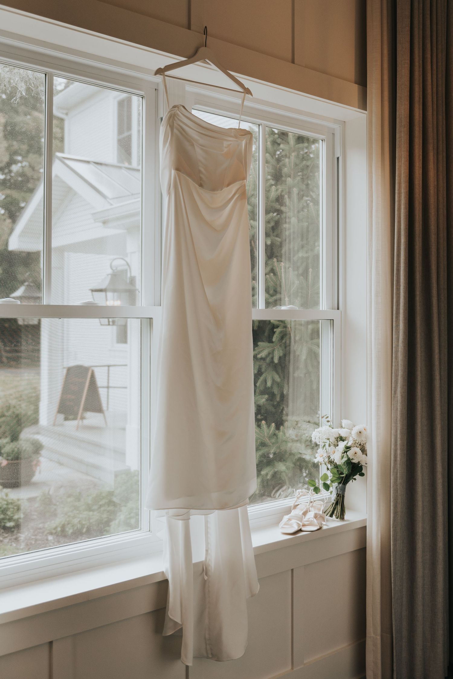 White curtains and linens hanging in a bright sunlit room with large windows and natural lighting.
