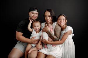 A black and white studio portrait series showing intimate family moments with children and adults in white clothing.