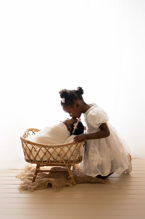 A series of sepia-toned photos showing children in white dresses looking into vintage wicker bassinets.