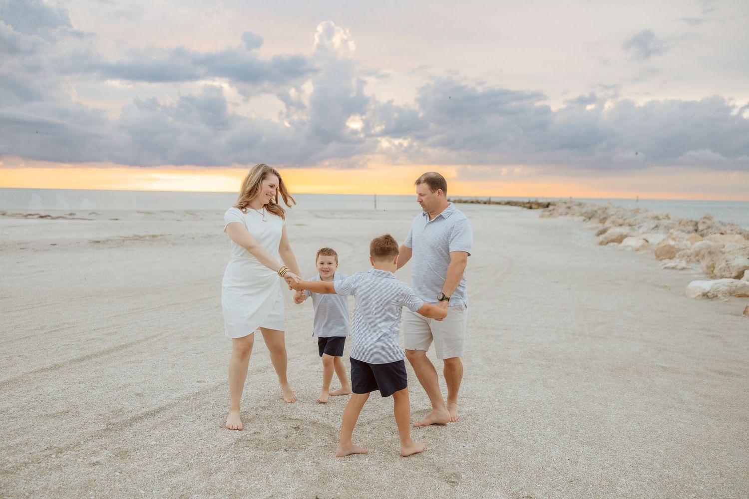 Lifestyle family session capturing parents and children running and playing together on the beach at sunset.