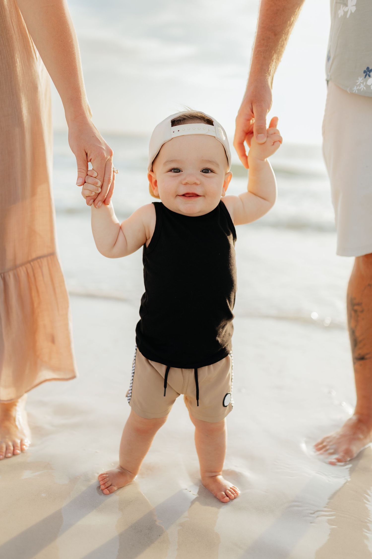 Beach family portrait of parents standing together with their child during a relaxed lifestyle session.