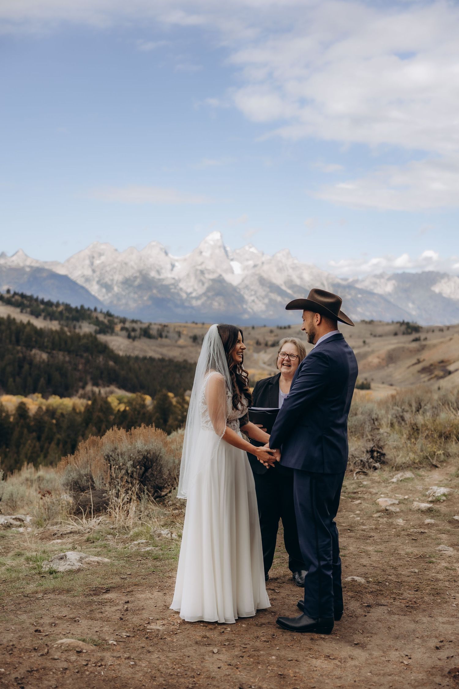 Intimate wedding ceremony taking place on a mountain ridge with snow-capped peaks in the background.