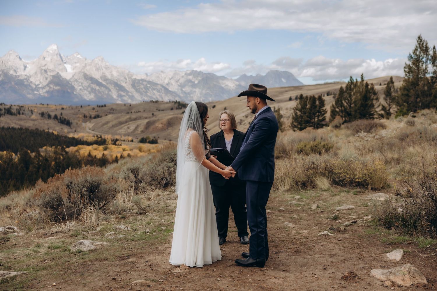 Scenic mountain wedding ceremony with dramatic snow-capped peaks and golden autumn landscape in the background.